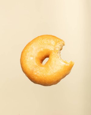 Yumuşak bir bej arka planda yüzen ısırık jöleli çörek. Pastane, tatlı veya aperatif tasarımlar ve modern görsel projeler için ideal minimum ve yaratıcı gıda kavramı.