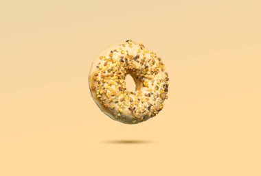 Şekerli donut ve pastel sarısı arka planda doğranmış fındık. Modern fırın, tatlı ya da abur cubur reklamı için mükemmel yaratıcı, minimal bir gıda konsepti..
