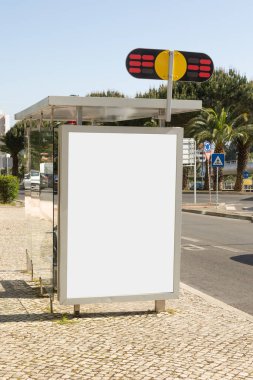 Portekiz 'de güneşli bir otobüs durağında boş bir ilan panosu. Etrafı palmiye ağaçları ve temiz kentsel tasarım ile çevrili. Modern ve canlı bir şehir ortamında reklam vermek için mükemmel..
