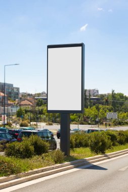 Portekiz 'in güneşli bir kentsel caddesinde boş dikey dijital ilan panosu. Arka planda açık mavi gökyüzü ve şehir mimarisi ile modelleme, reklam ve pazarlama tasarım sunumları için ideal.