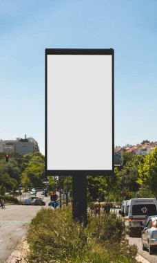 Portekiz 'in güneşli bir kentsel caddesinde boş dikey dijital ilan panosu. Arka planda açık mavi gökyüzü ve şehir mimarisi ile modelleme, reklam ve pazarlama tasarım sunumları için ideal.