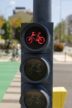 Lizbon, Portekiz 'de güneşli bir günde kırmızı bisiklet trafik ışıklarına yakın çekim. Arka planda modern bir bisiklet şeridiyle şehir bisiklet altyapısını ve şehir taşımacılık güvenliğini yakalar.