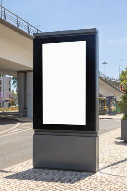 Yeşil bitkiler, ağaçlar ve açık mavi gökyüzü olan şehir merkezindeki boş dijital ilan panosu. Açık hava reklamları, iş kampanyaları ya da tanıtım mesajları için mükemmel bir yer..