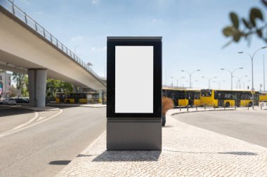 Lizbon otobüs terminalindeki boş dikey reklam panosunun arka planında sarı otobüsler ve yükseltilmiş yol modern şehir manzaralı güneşli bir günde kentsel reklamlar için mükemmel bir model..