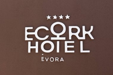 Ecorkhotel vora logosu kahverengi bir duvarda, modern beyaz harfler ve dört yıldızlı, Güney Portekiz 'de lüks bir çevre dostu oteli gösteriyor..