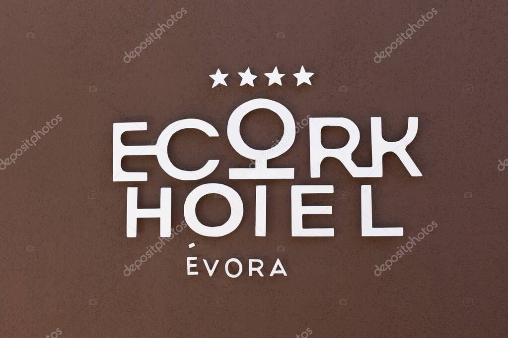 The logo of Ecorkhotel vora is displayed on a brown wall, featuring modern white lettering and four stars, indicating a luxury eco-friendly hotel in southern Portugal.