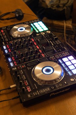 Profesyonel DJ karıştırıcı ve ışıklı düğmeleri ve düğmeleri olan kontrolör. Modern müzik ekipmanları ahşap bir masada, parçaları karıştırmaya hazır. DJ 'ler, partiler ve elektronik müzik etkinlikleri için gerekli malzemeler.