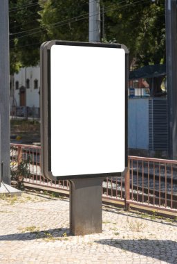 Tramvay raylarının yakınındaki kaldırımda dikey boş reklam panosu, kentsel arka plan ve ağaçlar. Model sunumlar, reklam kampanyaları ve pazarlama promosyonları için mükemmel..