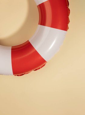 Yumuşak pastel arka planda kırmızı ve beyaz şişme bir can simidi. Deniz kenarındaki güvenlik, eğlence ve rahatlamayı simgeleyen minimalist ve canlı bir yaz temalı görüntü..