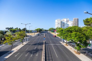 09-08-2025, Restelo Lisboa. Güneşli bir günde Restelo, Lizbon, Portekiz 'de geniş bir cadde manzarası. Yol birden fazla şeride bölünmüş ve bazı arabalar geçiyor..