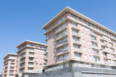 Açık mavi gökyüzünün altında balkonları olan modern apartmanlar.