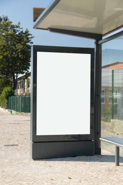 Lizbon, Portekiz 'de bir kaldırımda dikey boş reklam panosu. Arka planda binalar ve yeşillik olan bir yolun yanında..