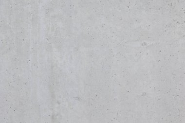 Ham beton duvarın yakın çekim dokusu. Yüzey doğal kusurları, küçük delikleri ve renk çeşitliliğini gösterir. Bitmemiş ya da endüstriyel tarzda tipik beton..