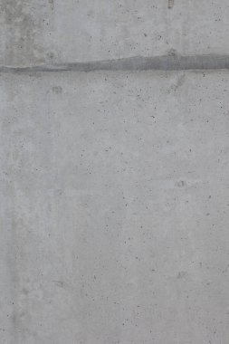 Ham beton duvarın yakın çekim dokusu. Yüzey doğal kusurları, küçük delikleri ve renk çeşitliliğini gösterir. Bitmemiş ya da endüstriyel tarzda tipik beton..