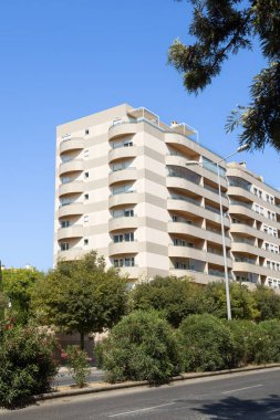 Lizbon, Portekiz 'de, eğimli balkonları ve çağdaş mimarisi olan modern bir yerleşim yeri. Önünde mavi gökyüzü ve yeşil ağaçlar olan şehir yaşam tarzı konsepti. Gayrimenkul temaları için ideal görüntü.