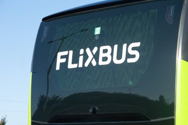 Lisbon, Portugal - September 29, 2025: Close-up of the rear window of a FlixBus coach, showing the companys white logo on the glass with reflections of trees and sky.