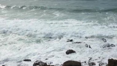 Ocean waves crashing on rocks at Praia das Mas in Sintra, Portugal