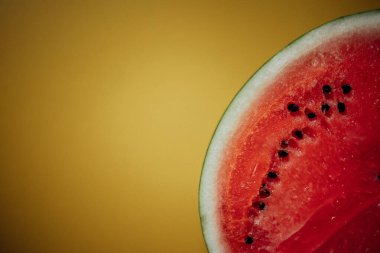 Sarı arka planda dilimlenmiş karpuz. Canlı sarı arka planda taze kesilmiş sulu bir karpuz. Yaz ve yemekle ilgili tasarımlar için parlak ve taze bir görüntü..