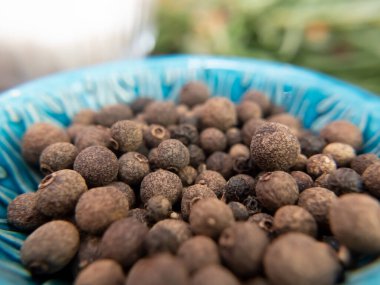 Mavi kasede siyah biber, yakın plan çekilmiş, geniş bir alan derinliğinde. Makro yiyecekler hala hayattadır. Yüksek kalite fotoğraf