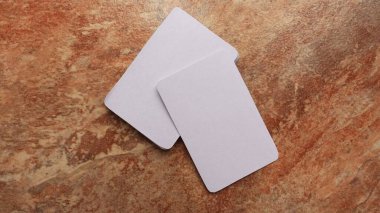 Kart oynuyorum, modern modeller yapıyorum. Kahverengi ve bej mermer bir yüzey üzerinde iskambil kağıdı. Boş beyaz kartlar ya da kartvizitler. Marka ve tatiller. 