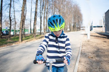 Mobiletli, koruyucu miğferli küçük bir çocuk. Şehrin sokaklarındaki güvenlik çocukları için popüler ekipmanları koruyor. Yüksek kalite fotoğraf