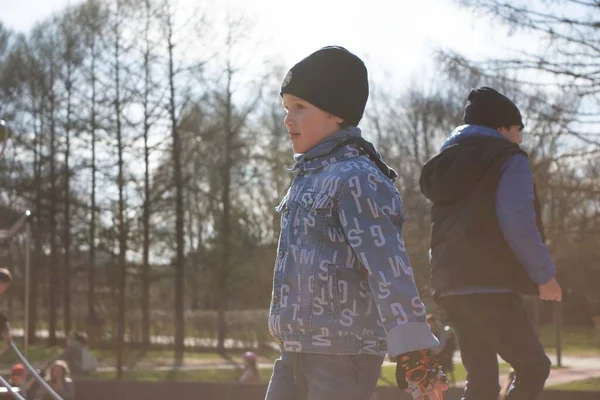 stock image A boy in a denim jacket is playing outside with other children. Spring childrens entertainment on the street. High quality photo