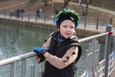 Mobiletli, koruyucu miğferli küçük bir çocuk. Şehrin sokaklarındaki güvenlik çocukları için popüler ekipmanları koruyor. Yüksek kalite fotoğraf