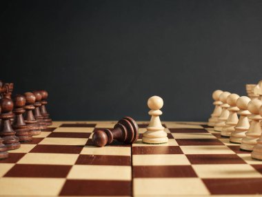 Satranç tahtasında satranç piyonu yüz yüze. Beyaz satrancın zaferi ve siyah piyonun kaybı..