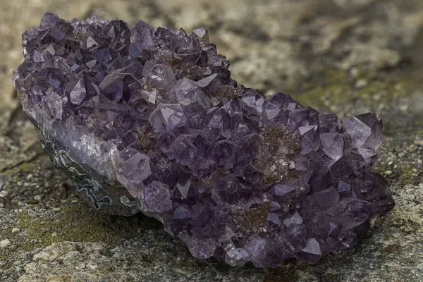 Ham bir matris üzerinde sayısız iyi şekillendirilmiş mor kristaller barındıran canlı ametist druse doğal ışık koşulları altında dokulu bir taş zemin üzerinde güzel bir şekilde ele geçirildi.