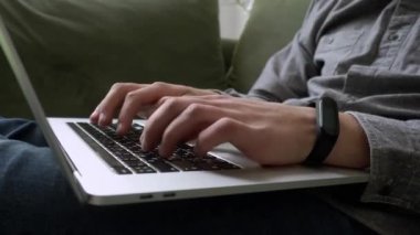 İş kadınının elleri. Dizüstü bilgisayar klavyesinde daktilo kullanan kullanıcı. Evde kanepede oturup bilgisayarla çalışmak. Teknoloji konsepti. Yan görüntüyü kapat. Video 4K