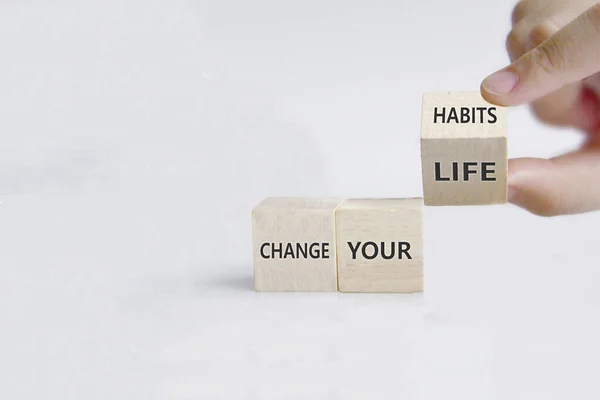 Hand turns dice and changes the slogan \'change your habits\' to \'change your life\'.