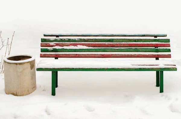 snow covered wooden sitting bench in park at winter.