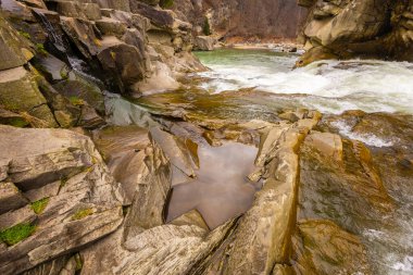 Ukrayna Karpatları 'nda manzaralı bir bahar şelalesi. Büyük kahverengi kayaların arasında güzel bir nehir akıyor..