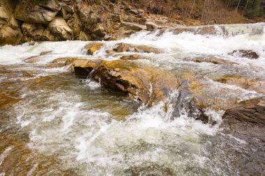 Ukrayna Karpatları 'nda manzaralı bir bahar şelalesi. Büyük kahverengi kayaların arasında güzel bir nehir akıyor..