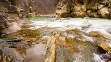 Ukrayna Karpatları 'nda manzaralı bir bahar şelalesi. Büyük kahverengi kayaların arasında güzel bir nehir akıyor..