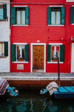 Burano, İtalya - Ekim 2022: Küçük tekneleri demirlemiş kırmızı renkli kanal manzaralı konut