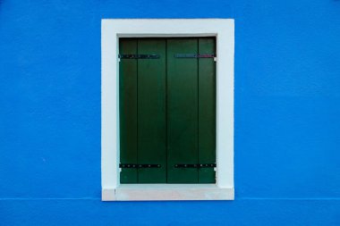 Mavi konut duvarında beyaz kenarlıklı pencere