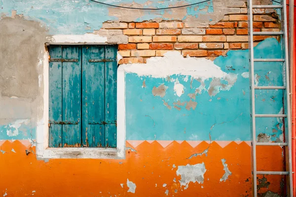 stock image Burano, Italy - October 2022: Ancient facade of dwelling with ruined orange and blue plaster