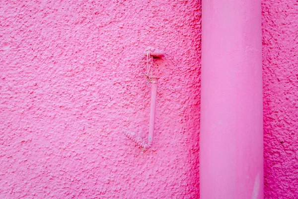 Detail of nail hanging on rose-colored wall in Burano