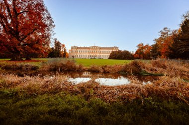Monza, Italy - November 2022: Monza's Villa Reale in autumn with tourists and small waterway in the foreground