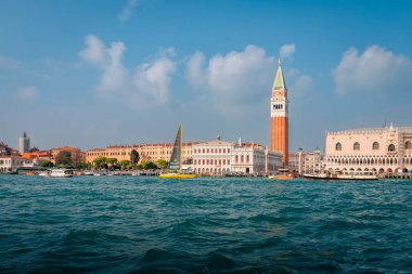 Venice, Italy - November 2022: The bell tower of San Marco in Venice taken from the sea with boats and blue sky and clouds