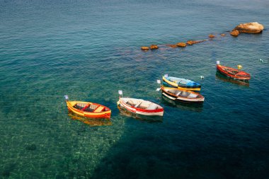 Taranto, İtalya - Temmuz 2023: Kayaların yakınındaki küçük renkli tekneler