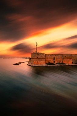 Taranto, İtalya - 19 Temmuz 2023: Günbatımında Taranto 'nun Aragonese Kalesi üzerinde uzun pozlu dikey görüş