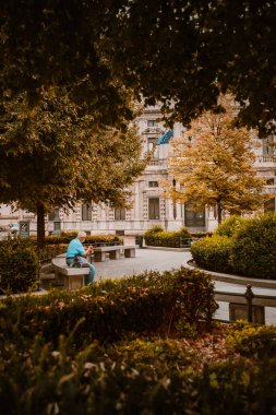 Milan, İtalya - Eylül 2023: Yaşlı bir adam parktaki bankta oturmuş düşünürken