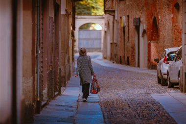 Pavia, İtalya - 20 Nisan 2024: Pavia 'nın tarihi şehir merkezinde yürüyen yaşlı kadın
