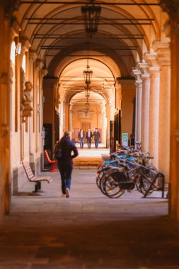 Pavia, İtalya - 20 Nisan 2024: Antik Pavia Üniversitesi 'nin çarşılarında yürüyen insanlar