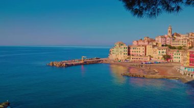 Büyüleyici Bogliasco köyü, açık mavi gökyüzü ile geleneksel Ligurian binalarının canlı renklerini yükselterek, yumuşak sabah ışığında yıkandı. Bu sahil taşının huzur dolu özünü yansıtan pitoresk bir manzara..