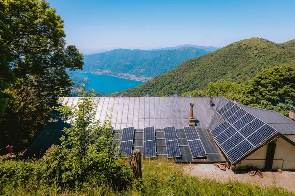 Monte Palanzone, Como - 22 Haziran 2025: Güneşli bir günde, Monte Palanzone 'nin uzak yeşil tepelerinde güneş panelleriyle sürdürülebilir bir enerji tesisi.