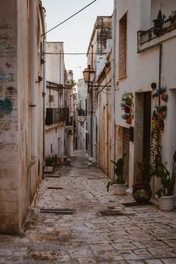 Oria, Brindisi - 7 Ağustos 2025: Oria 'nın tarihi merkezinde sıcak günbatımı parıltısı ve Akdeniz cazibesiyle taş döşeli bir sokak