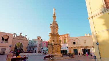 Piazza Salandra, Nardo 'daki barok kulede dikey kamera yükselişi heykel güzelliğini ve egemen varlığını vurguluyor.